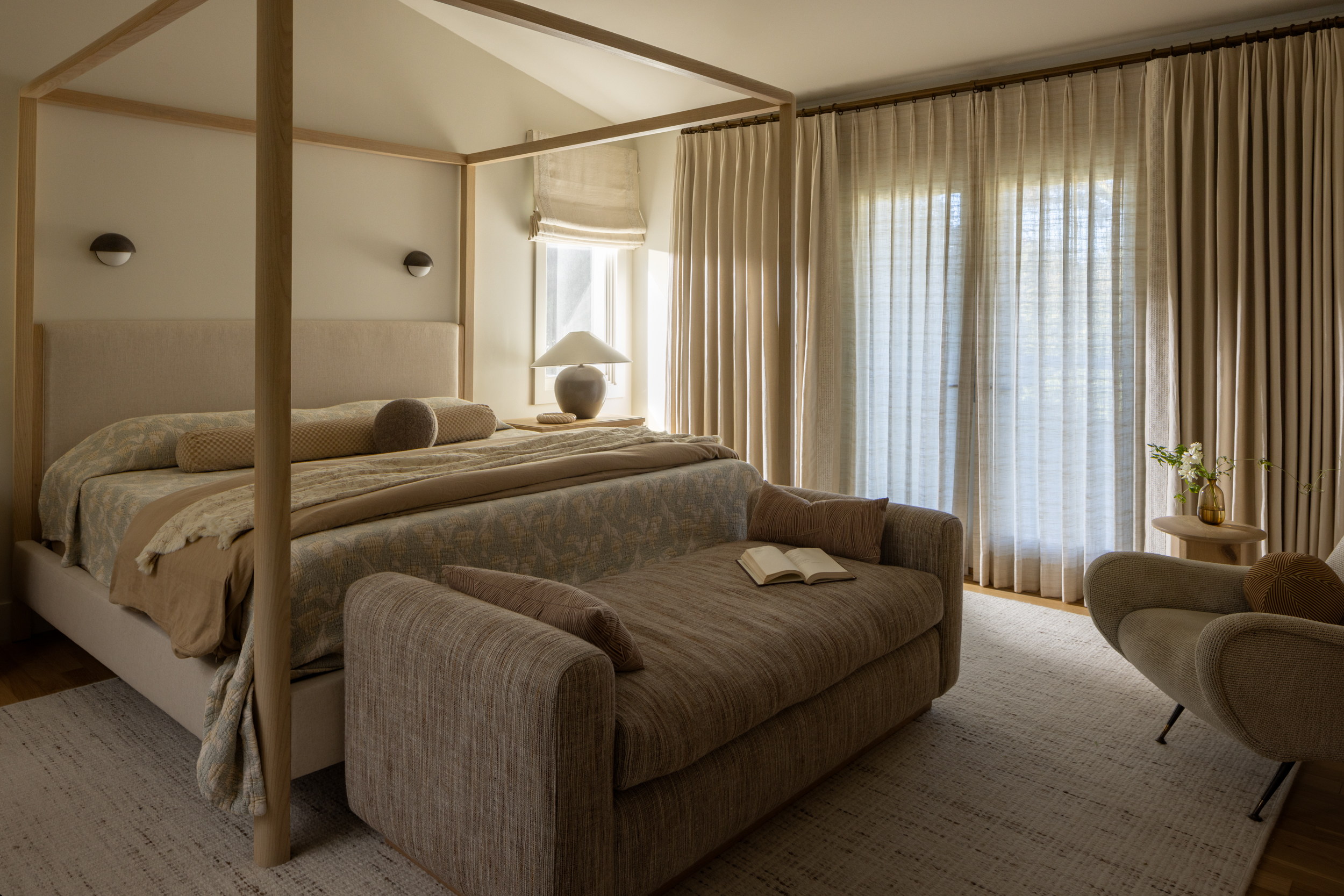 Elegant bedroom with four-poster bed, soft lighting, and cozy seating area.