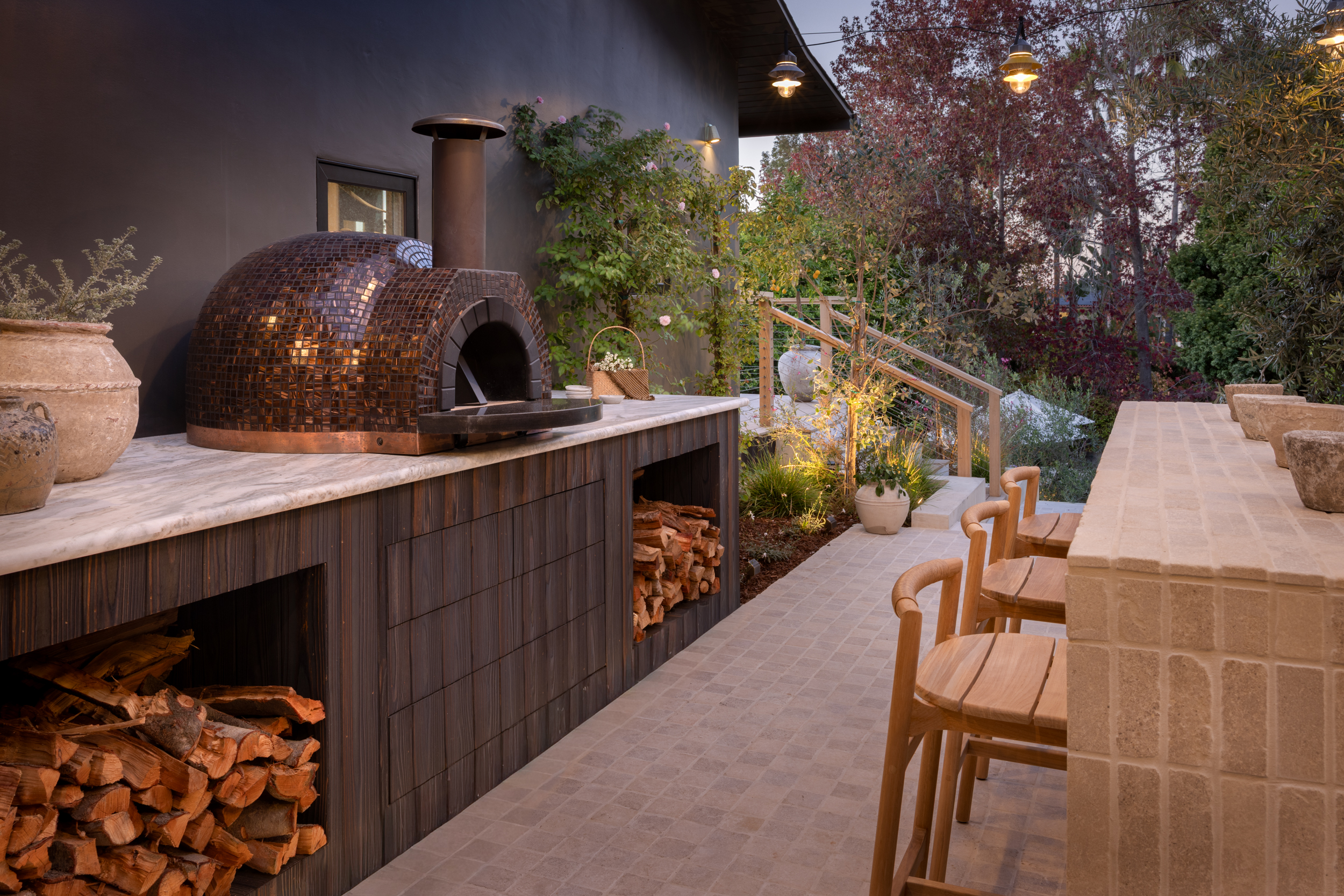 Outdoor kitchen with wood-fired oven and seating area at South Harlow Interiors.
