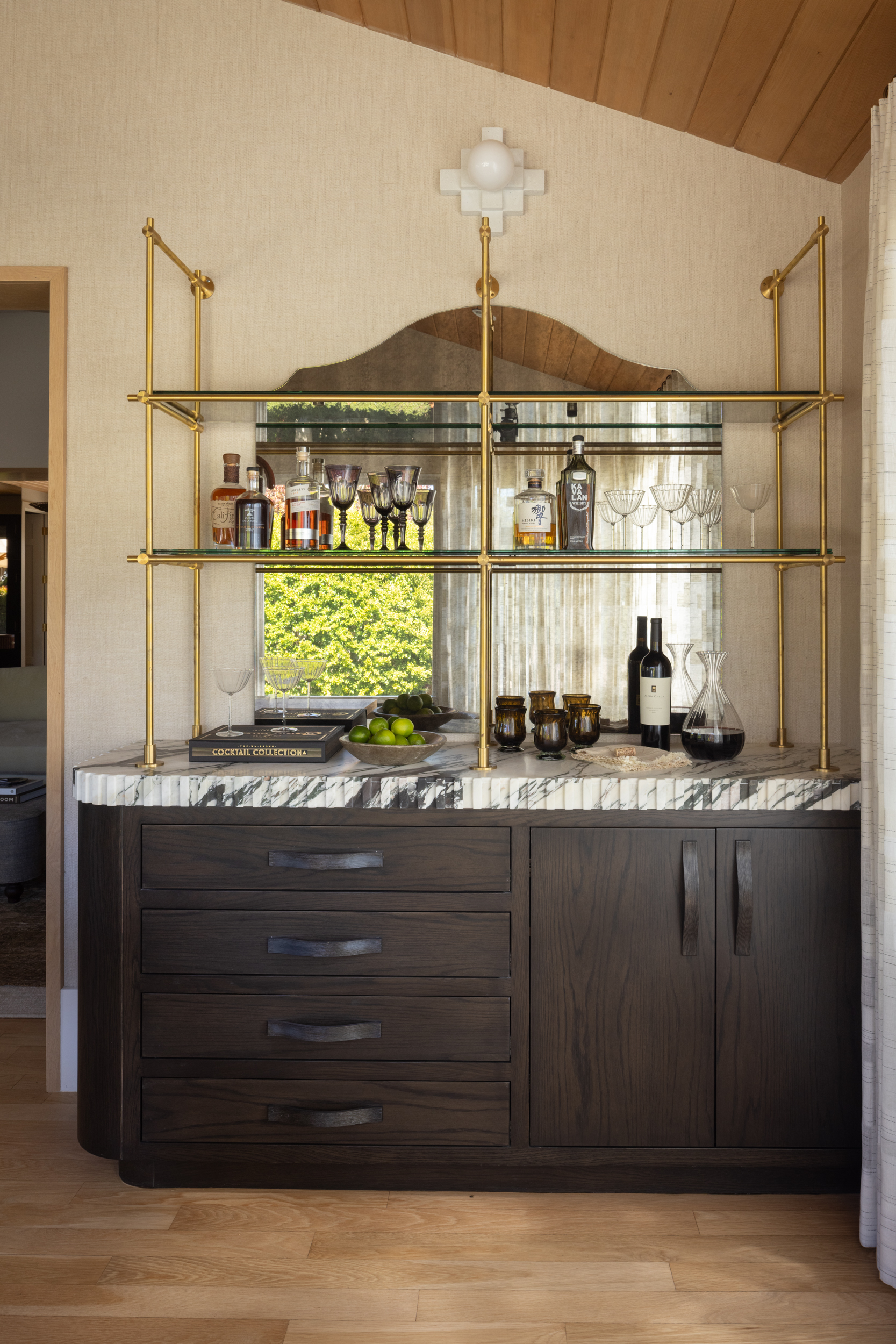 Elegant bar area with gold shelving and marble countertop in South Harlow Interiors.