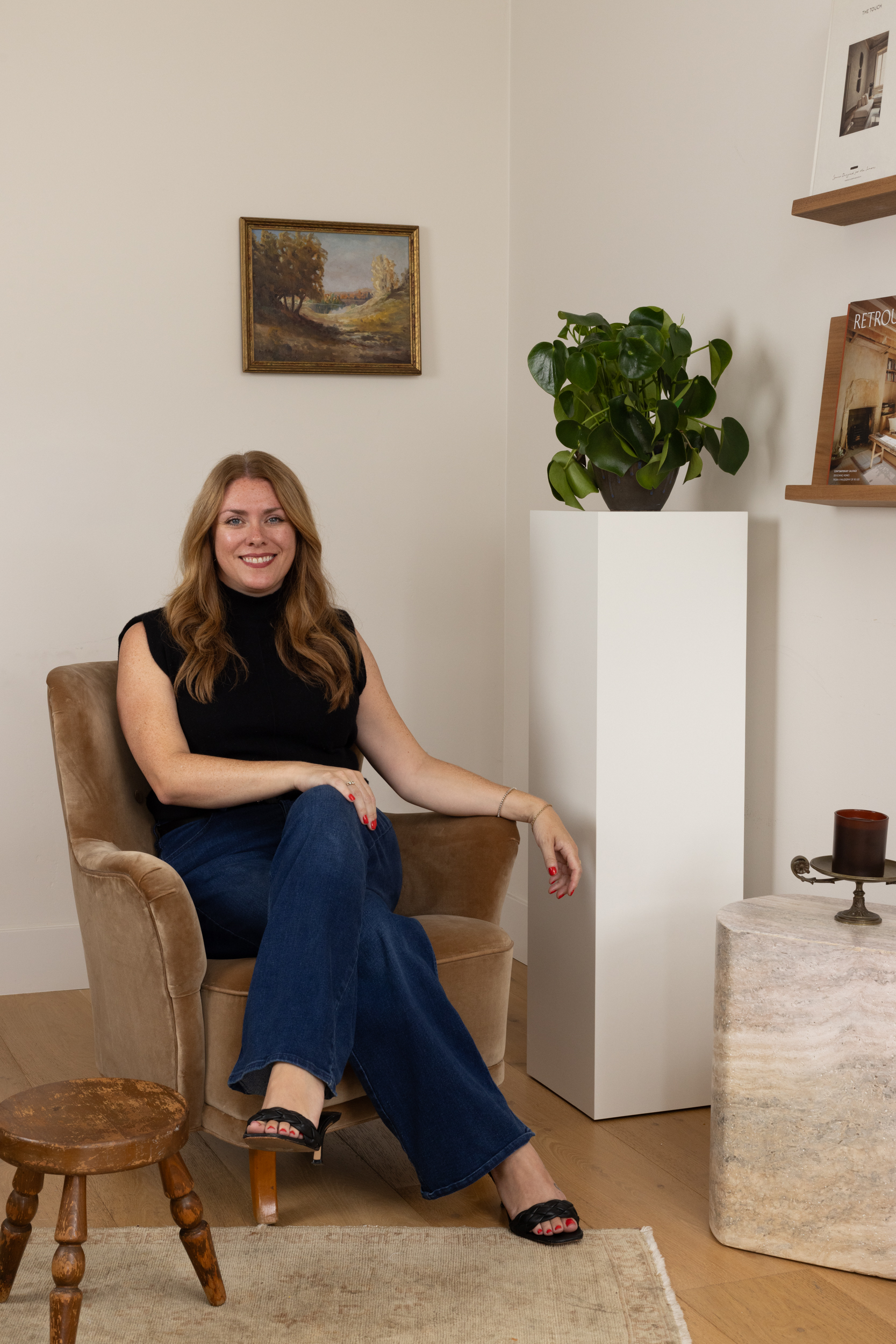 Woman sitting in a modern interior with plants and artwork at South Harlow Interiors.