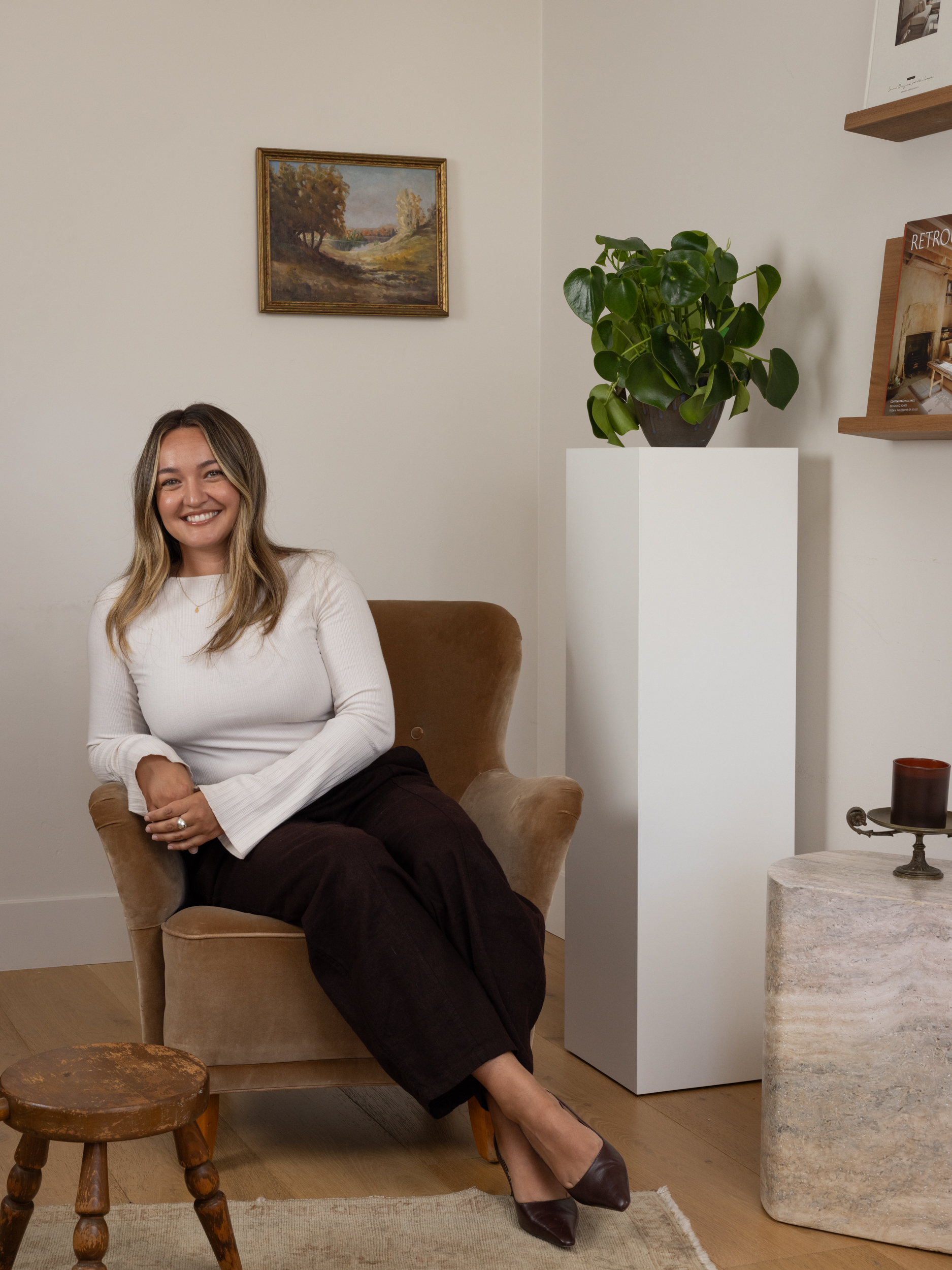 Woman sitting on a beige armchair in a modern interior space.