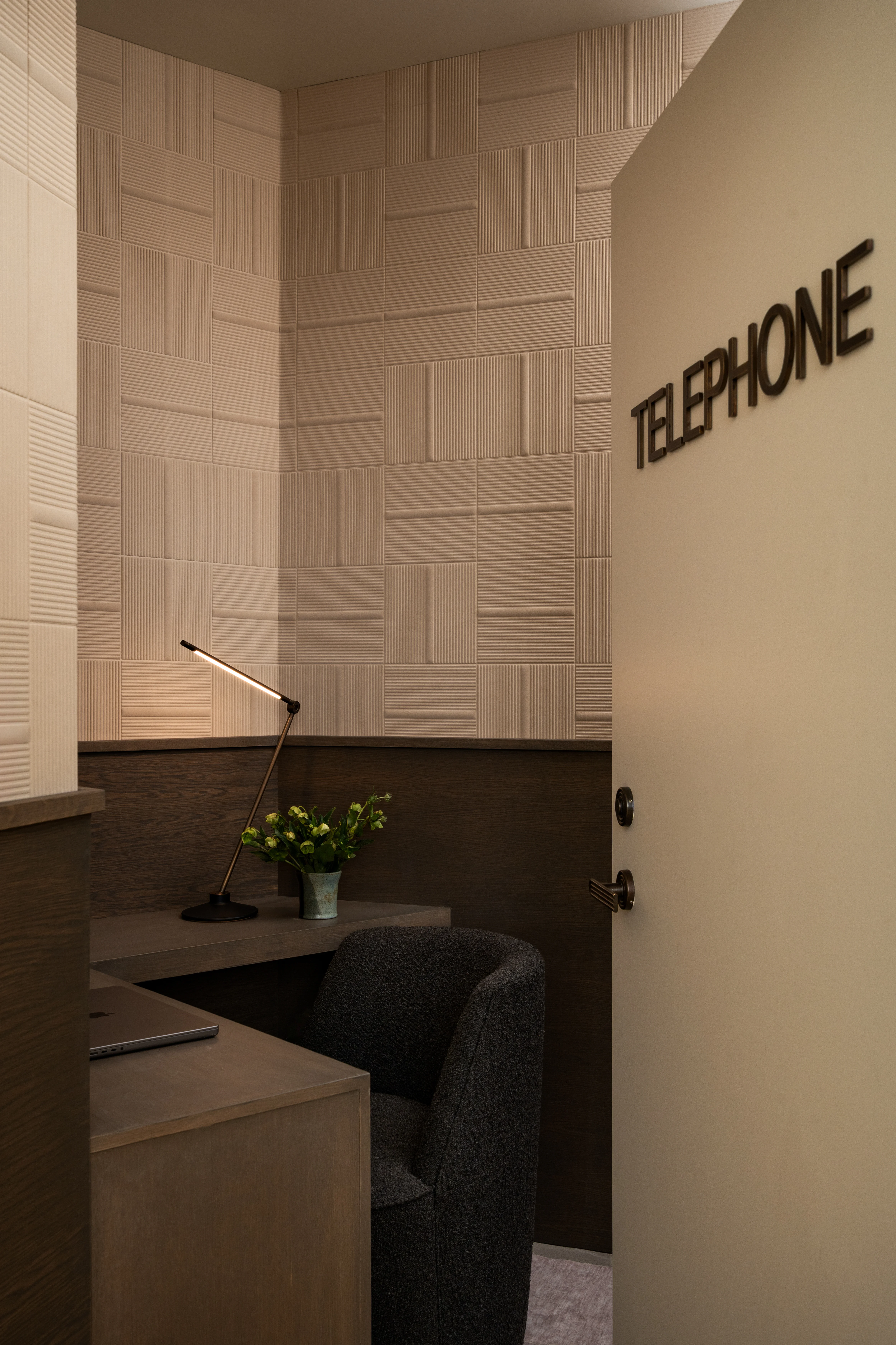 Compact telephone room with textured walls and a built-in desk.