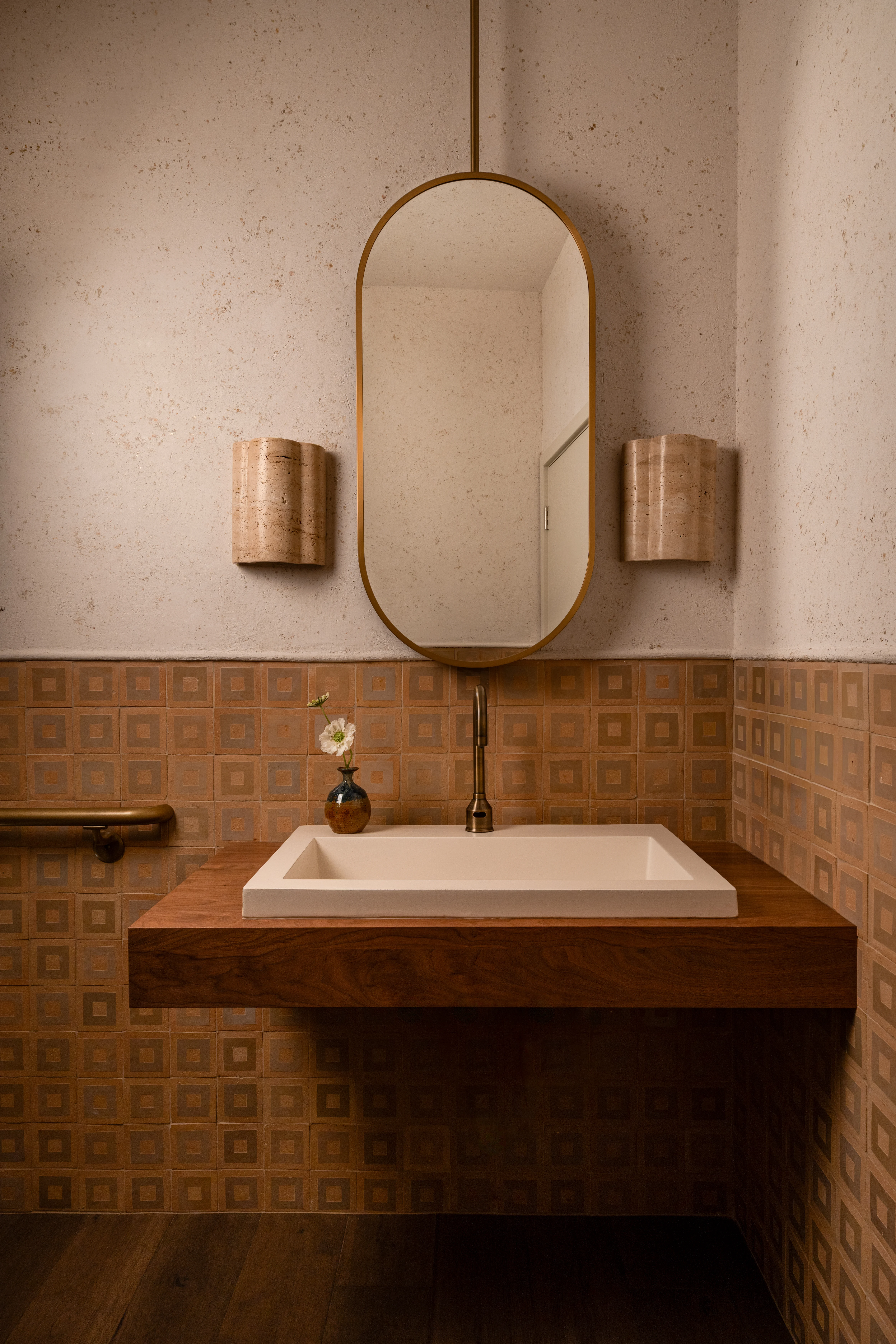 Terra-cotta tile powder room with an arched mirror.