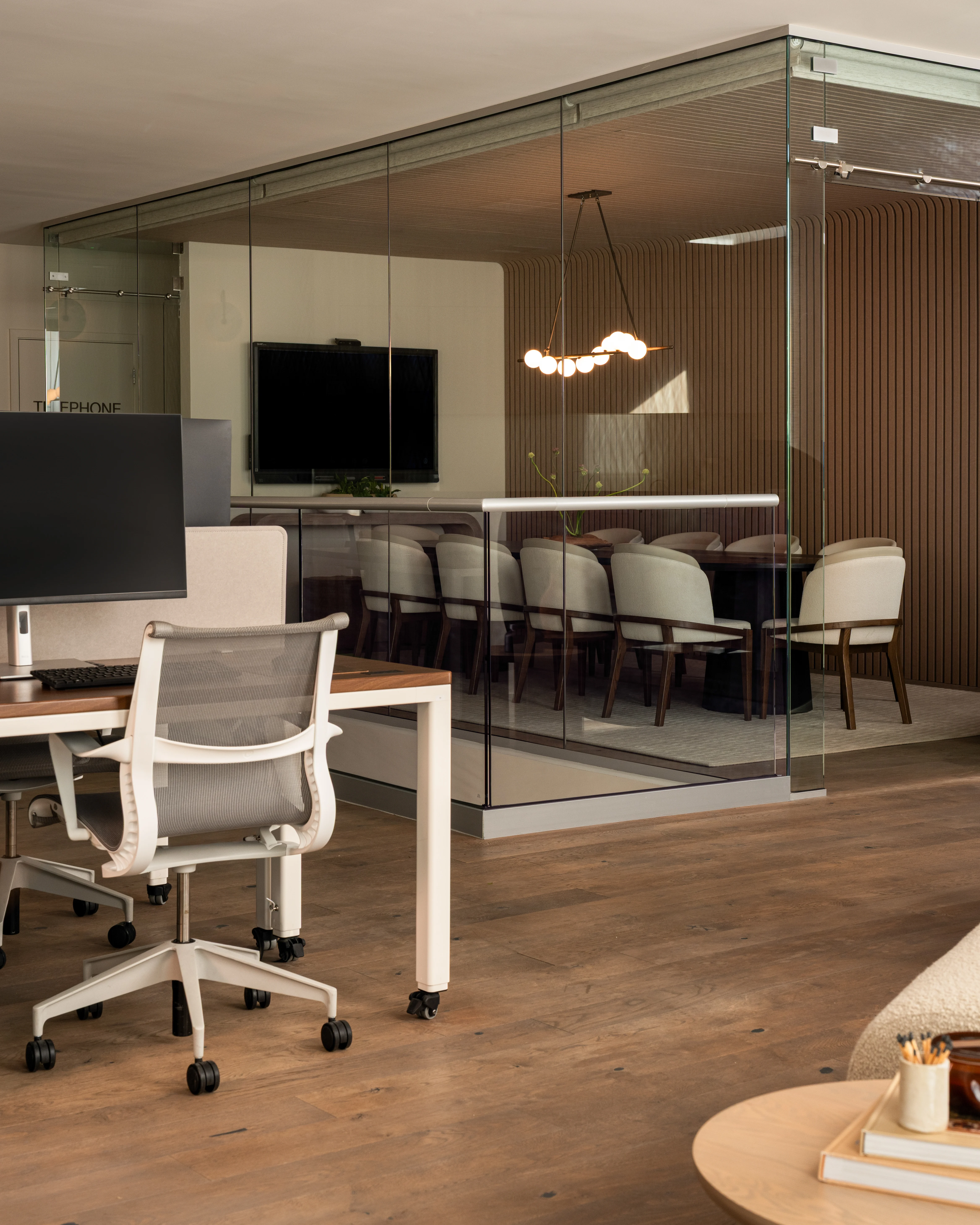 Open IOwn office with glass meeting room and collaborative workstations.