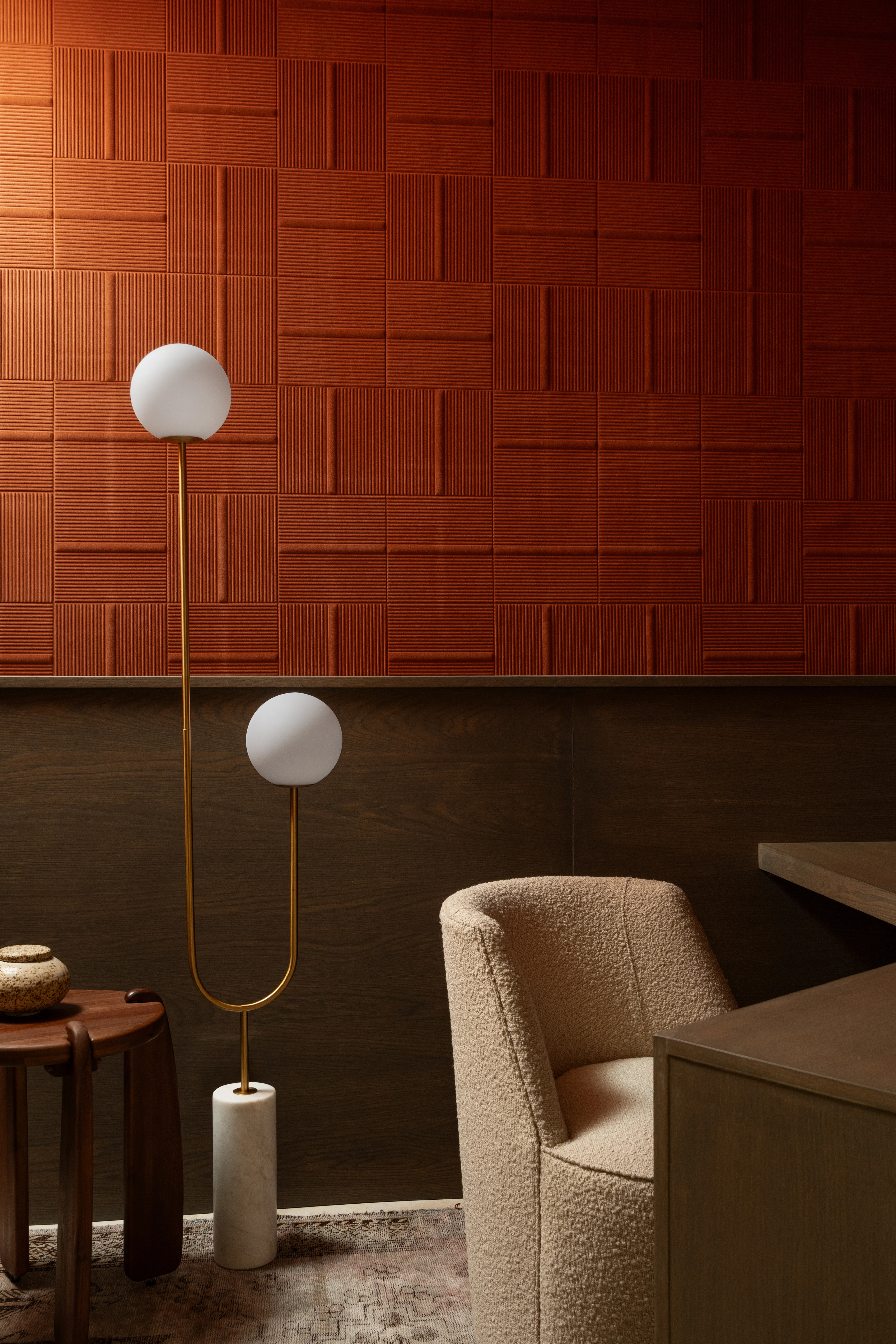 Sculptural lighting against a layered red tile office wall.