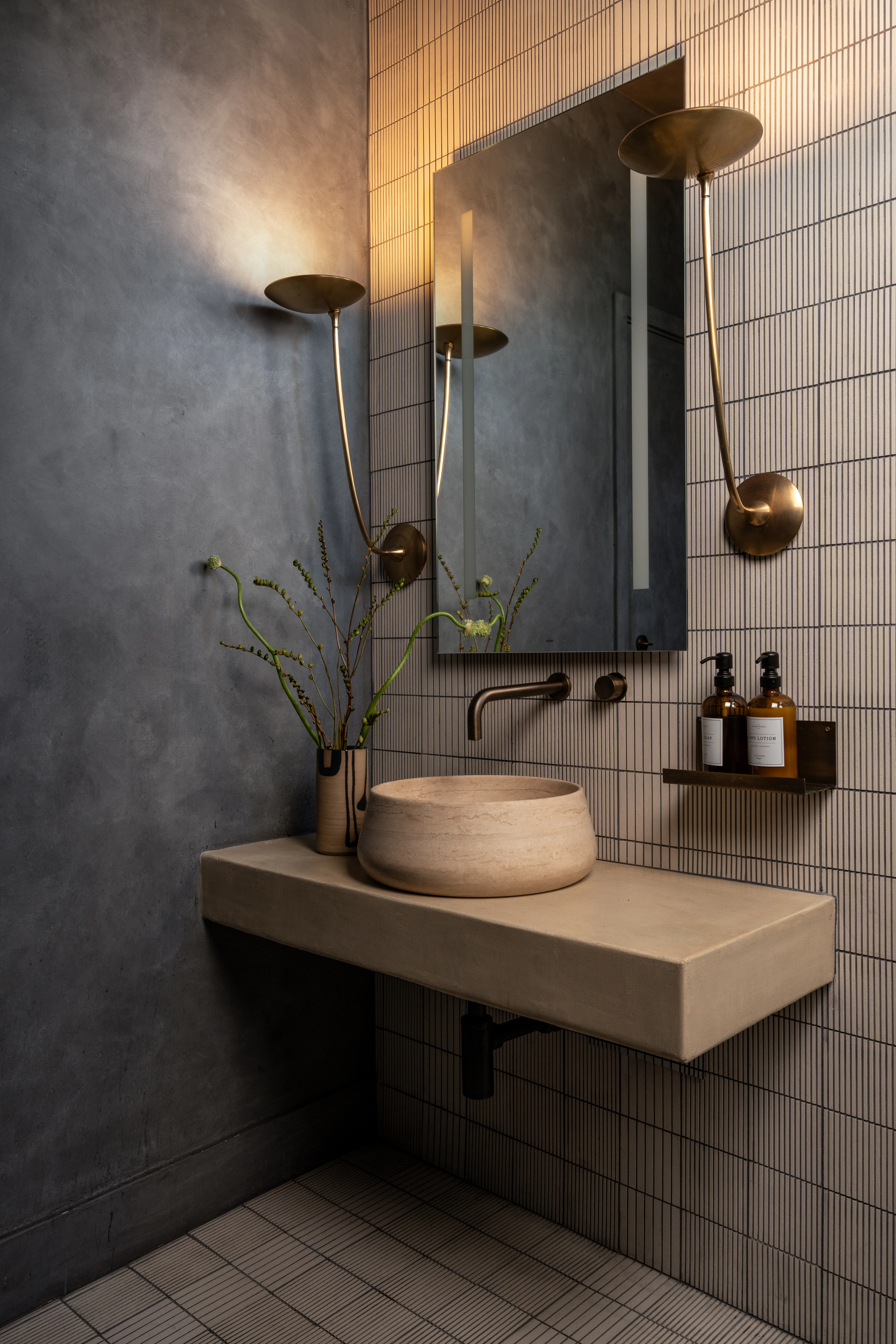 Blue tile spa bathroom with concrete sink and brass fixtures.
