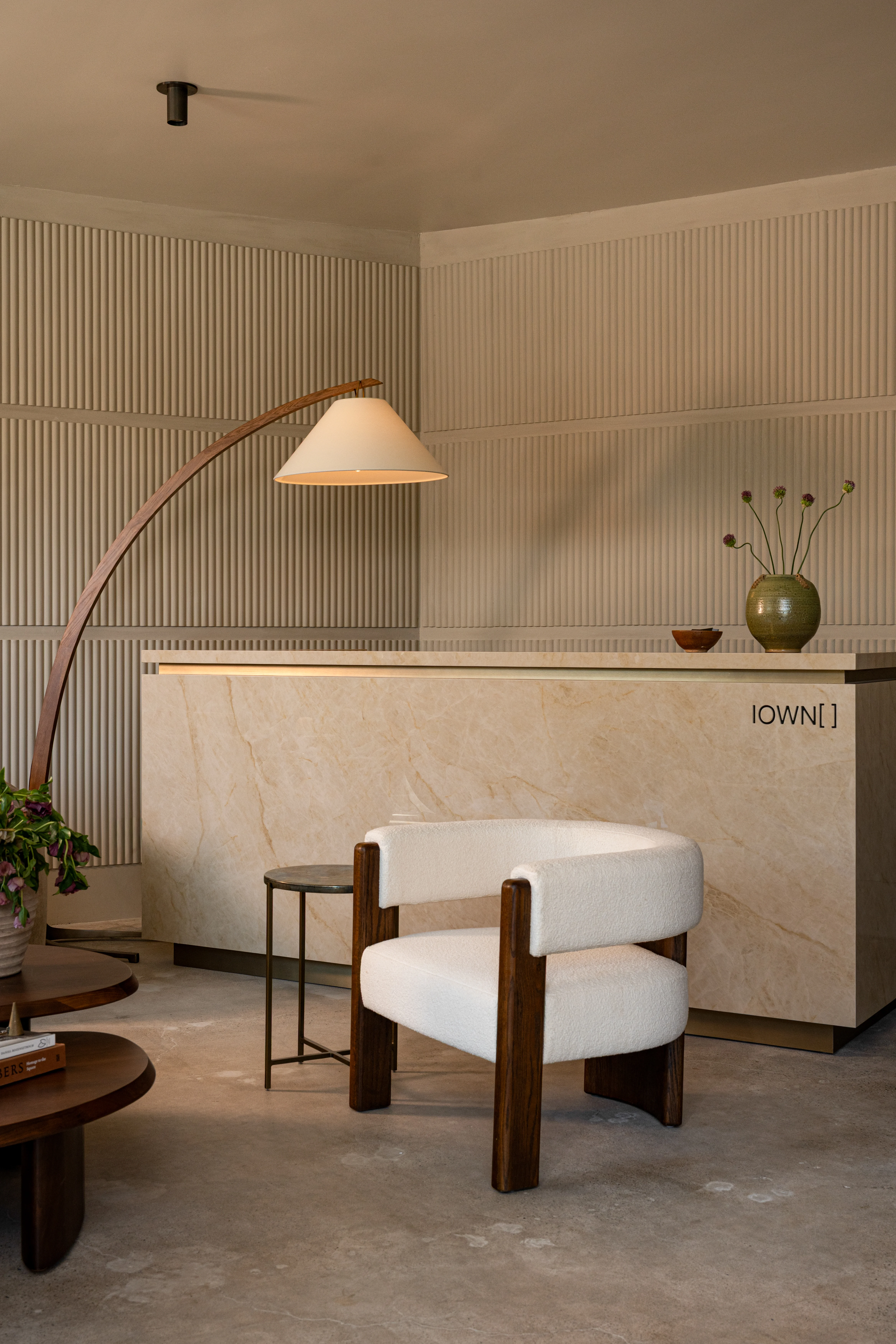 Curved stone reception desk beneath a sculptural floor lamp.