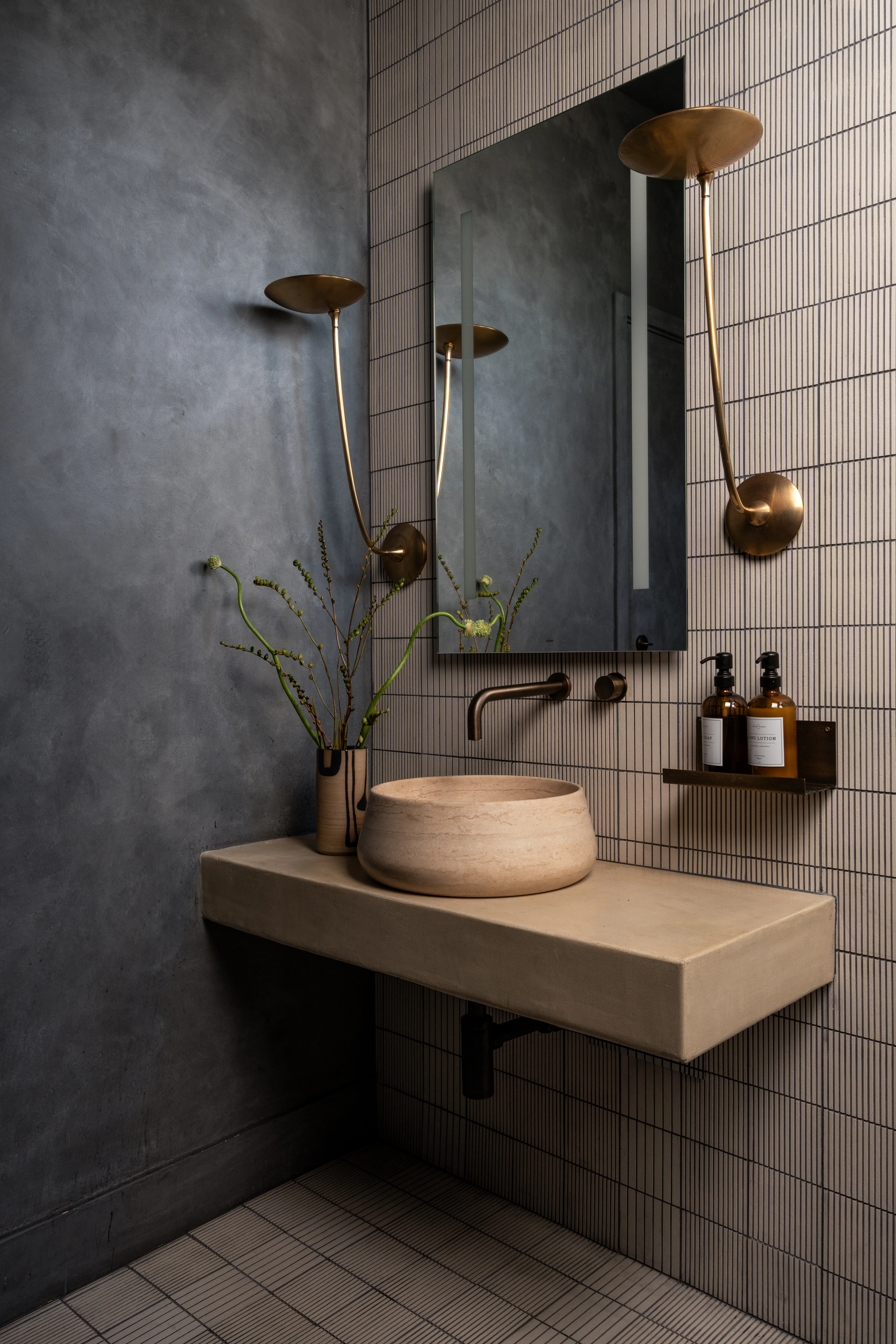 Concrete sink and brass fixtures in a blue tile spa bathroom.