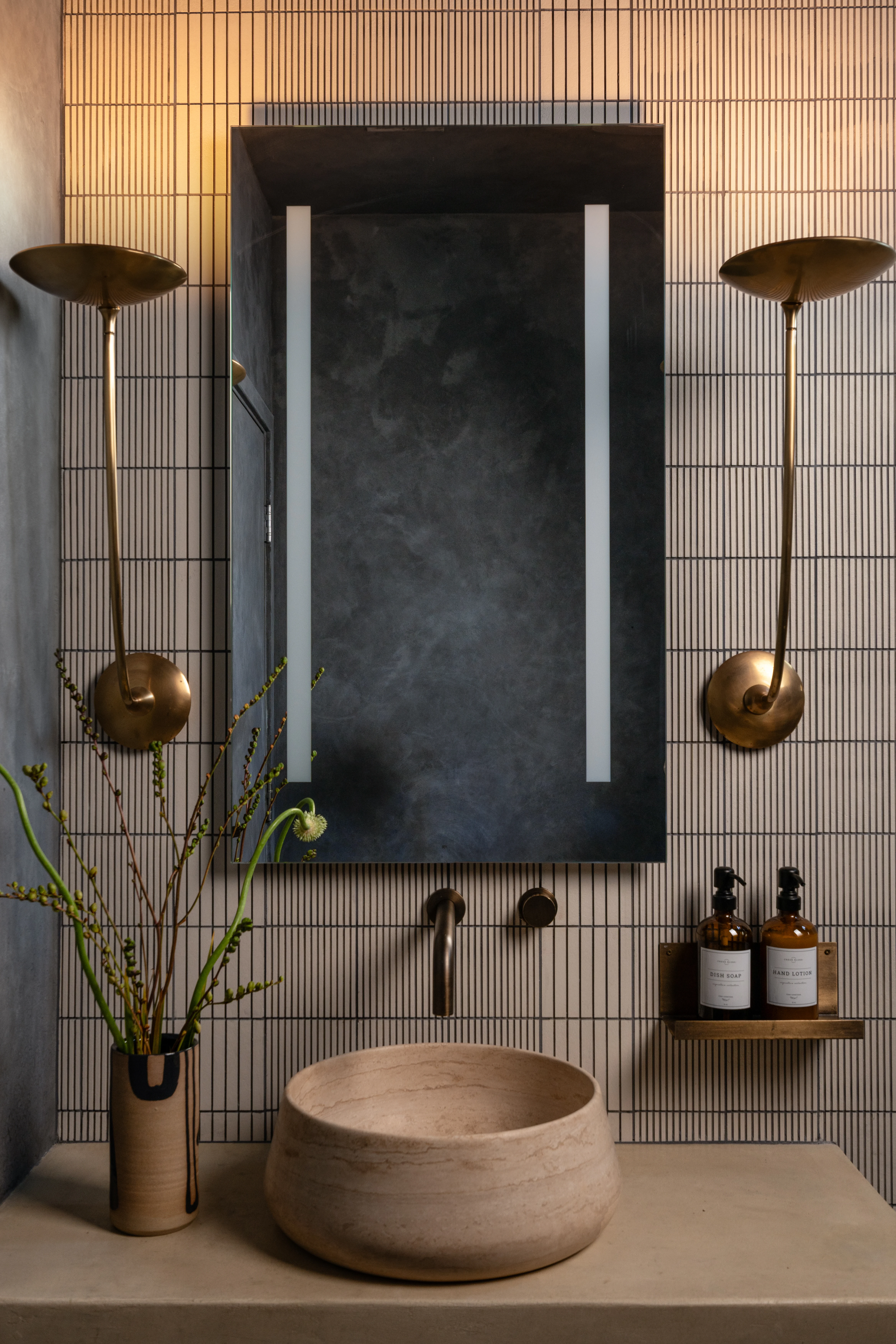 Sculptural stone basin beneath a dark framed mirror.