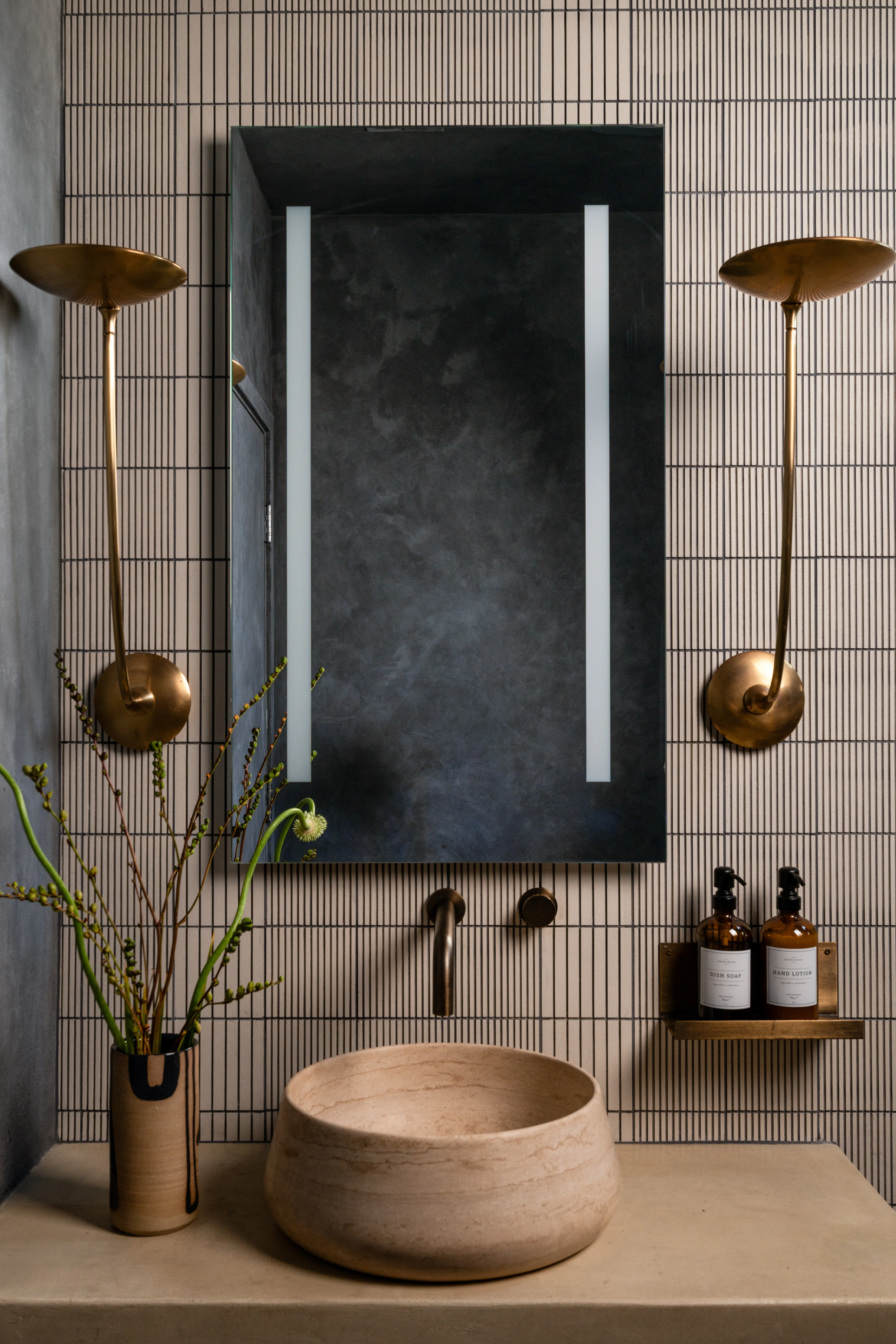 Blue tile bathroom with a sculptural basin and dark framed mirror.