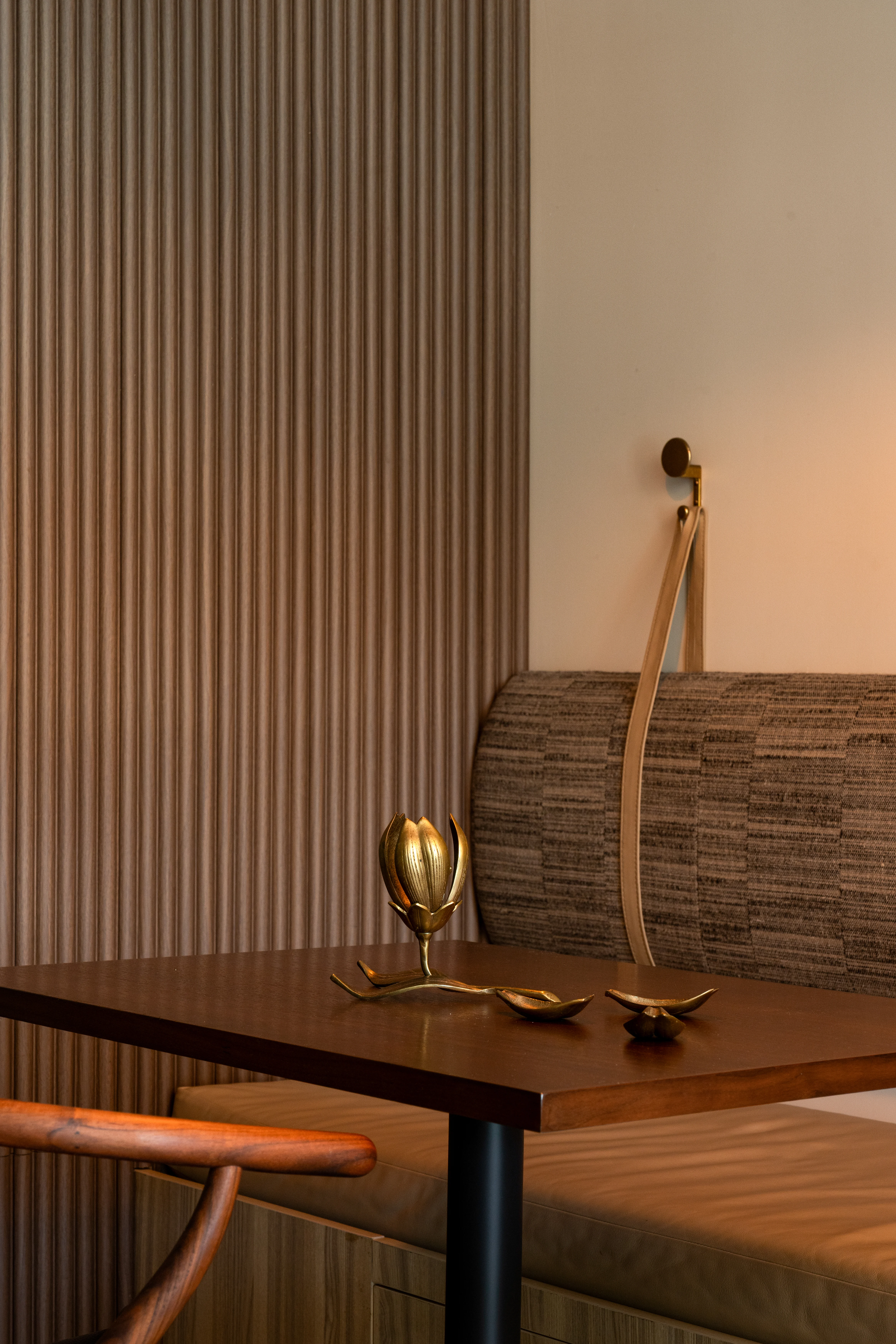 Private banquette workspace with fluted wall and brass sconce.