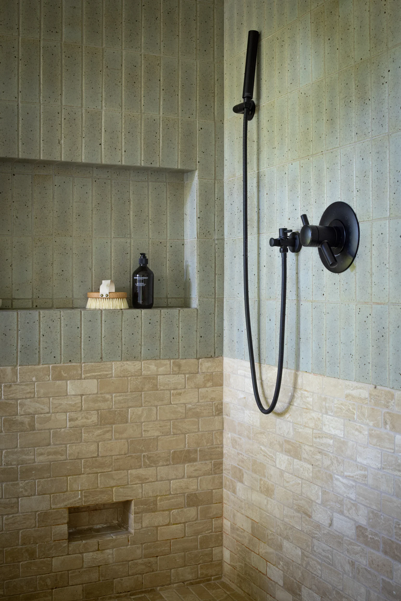 Walk-in shower with green vertical tile, recessed niche, and matte black fixtures.
