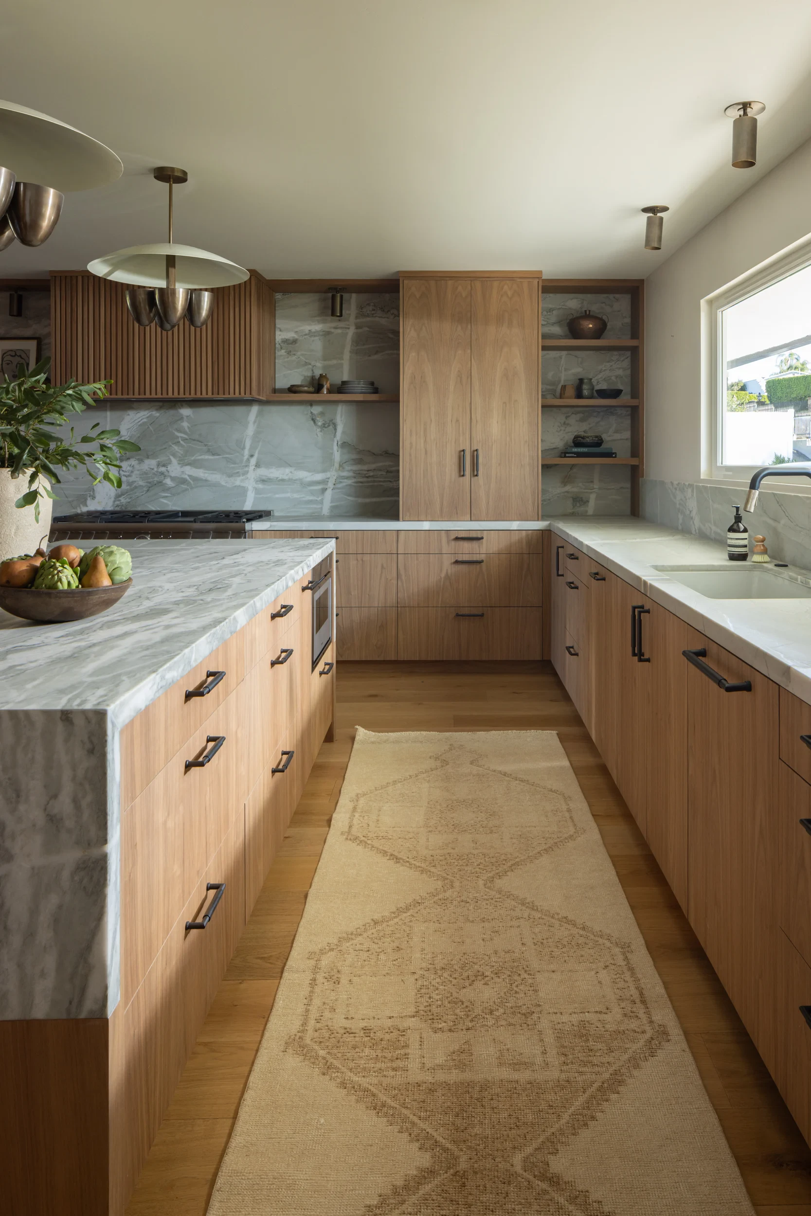 Kitchen galley run with walnut cabinetry, quartzite counters, and a vintage runner.