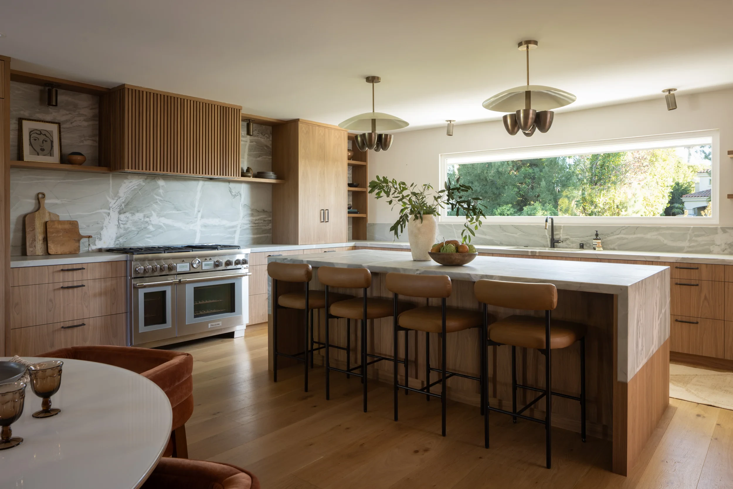 Open kitchen with walnut cabinetry, a quartzite island, and a long picture window.